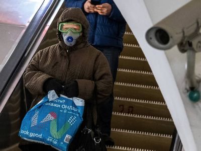 Пассажирка метрополитена в защитных очках, респираторе и перчатках на эскалаторе. Фото: Алексей Смагин / Коммерсант